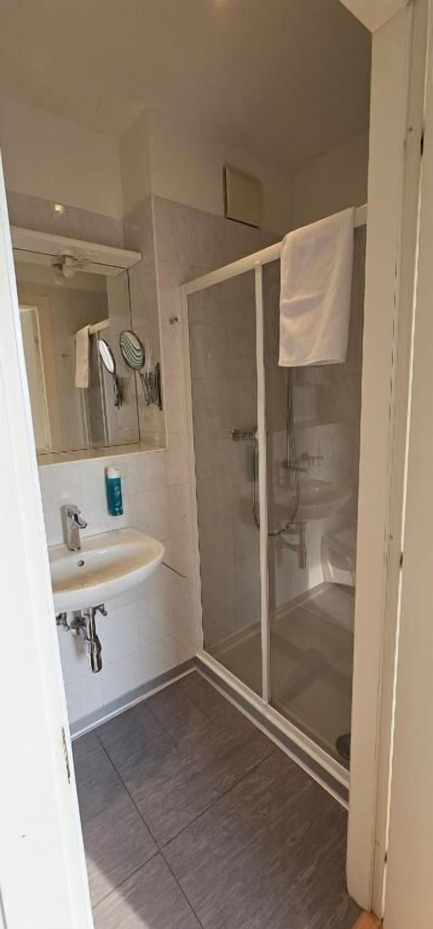 Une salle de bain avec une douche à parois de verre, un lavabo blanc et un miroir.