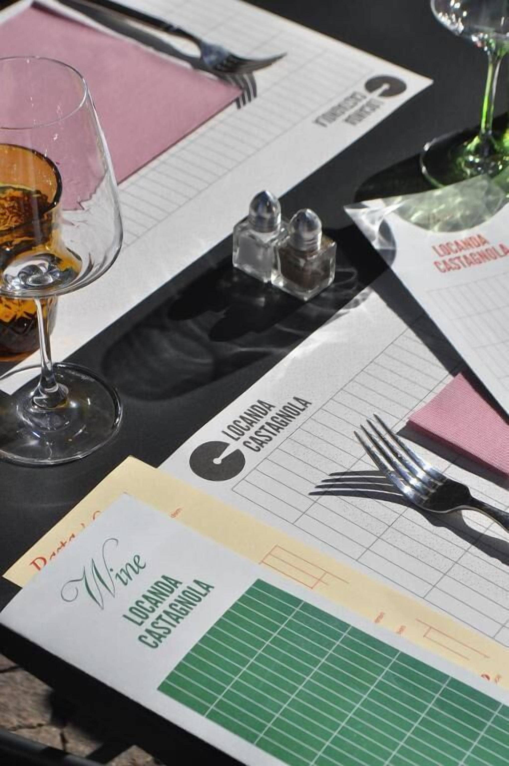 A table set with a menu, wine glass, and salt and pepper shakers.