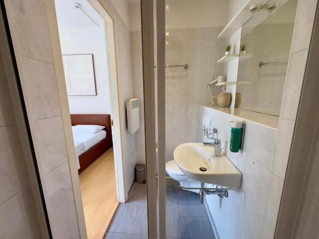 A modern bathroom with a glass shower enclosure, a white sink, and a mirror above it.