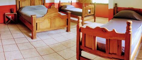 A room with two wooden beds, a small table, and a ceiling fan.