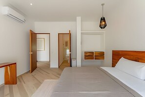 A modern bedroom with a large bed, wooden headboard, and a hanging light fixture.