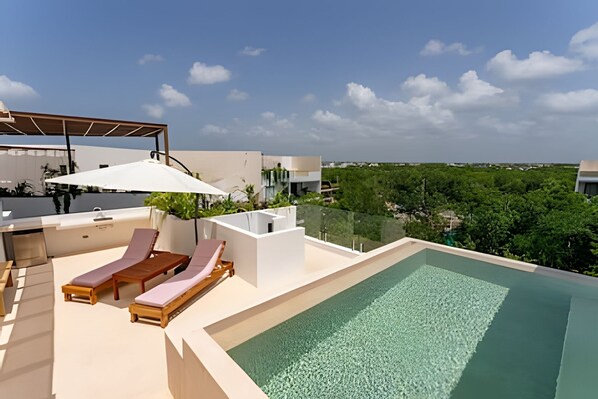 A rooftop pool area with lounge chairs and a pergola.