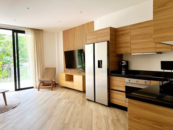 A modern kitchen with wooden cabinetry, a built-in TV, and a black countertop. - oasis yaaxlum (Tulum)