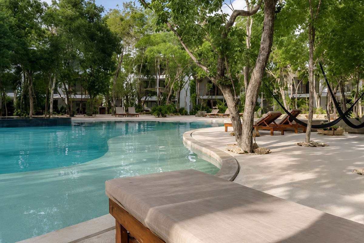 A pool area with lounge chairs and a hammock.