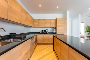 Eine moderne Küche mit Holzausstattung, einer schwarzen Arbeitsplatte und einer Edelstahl-Spüle.