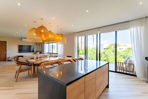 Eine moderne Küche mit einer zentralen Kochinsel, großen Fenstern und einem Essbereich mit Holzküchenmöbeln.