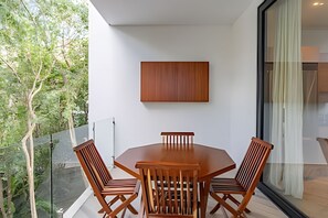 Ein moderner Essbereich mit Holztisch und -stühlen, einem großen Fenster und Blick auf Grün.
