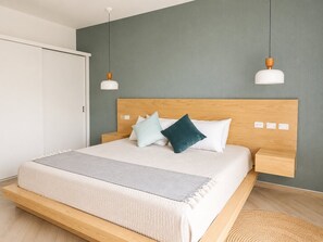 Une chambre moderne avec un cadre de lit en bois, un mur gris et une armoire blanche.