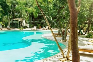 A pool surrounded by trees and lounge chairs. - oasis yaaxlum (Tulum)