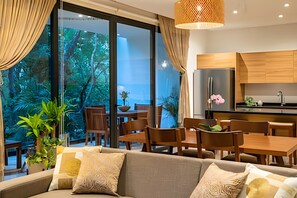 A modern living room with a sofa, dining area, and kitchen. - oasis yaaxlum (Tulum)