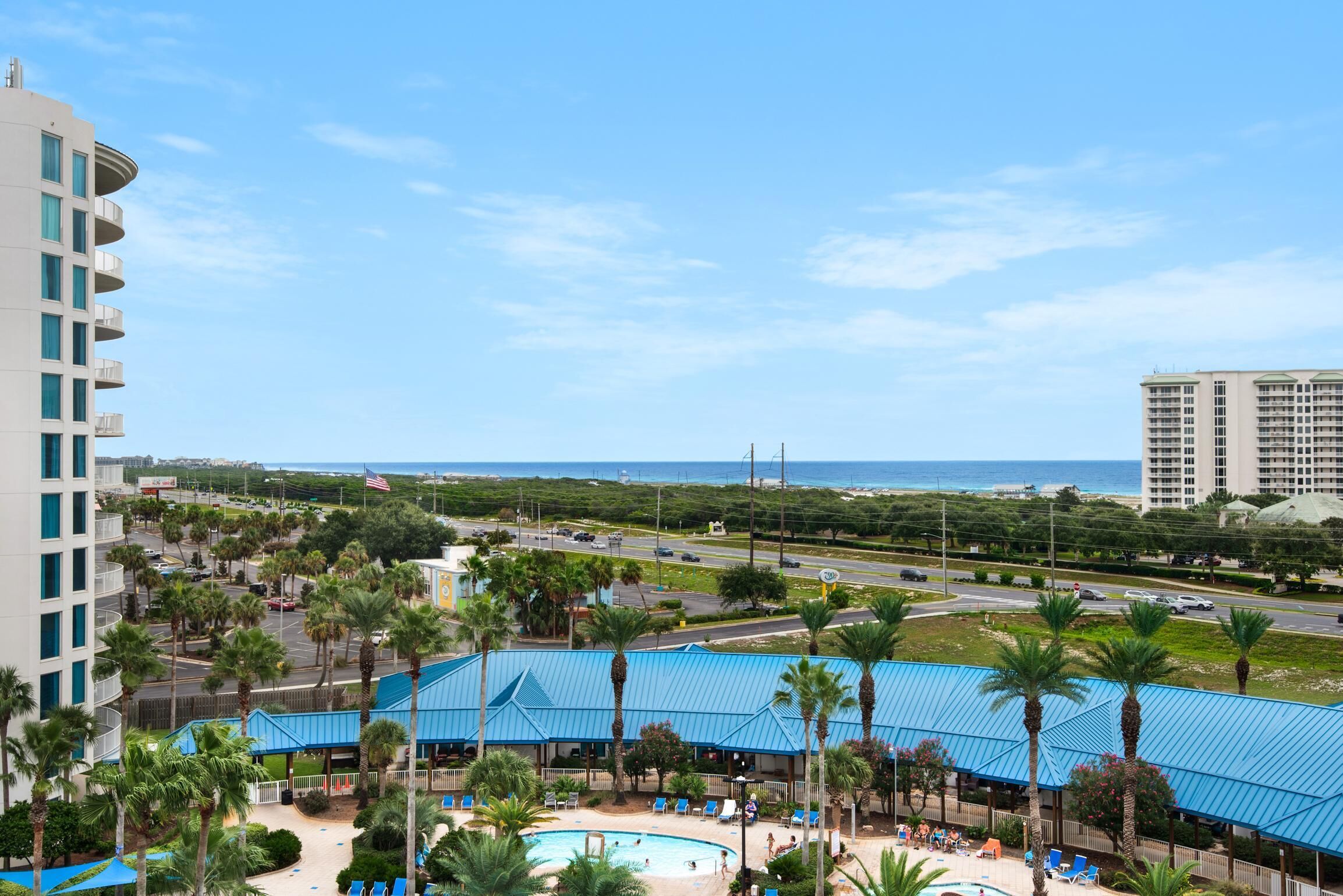 Ein Hotel mit Poolbereich, Palmen und Blick auf den Ozean.