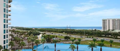 A hotel with a pool area, palm trees, and a view of the ocean.