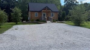 A log cabin with a gravel driveway and a wooden deck. - Deer View at Patoka Lake (Birdseye)