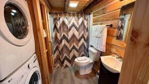 A compact bathroom with a washing machine, a toilet, and a sink. - Deer View at Patoka Lake (Birdseye)