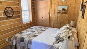 A wooden room with a bed, a lamp, a picture on the wall, and a window. - Deer View at Patoka Lake (Birdseye)