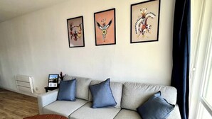A modern living room with a grey sofa, blue cushions, a wooden coffee table, and framed artwork on the wall. - Chez Béranger - near train station/congress center (Le Mans)