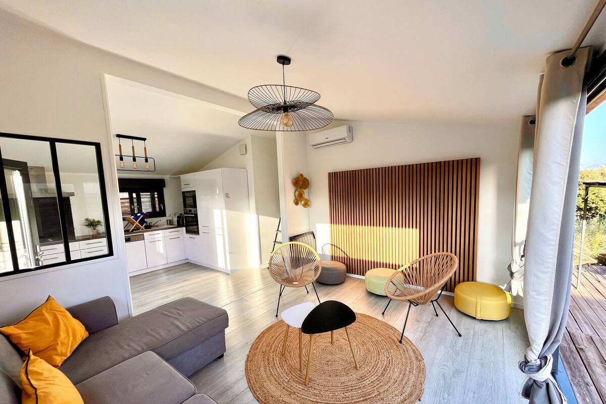 A modern living room with a sofa, chairs, a round rug, and a dining area with a table and chairs.