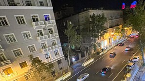 Una veduta notturna di una strada con edifici, auto e lampioni.