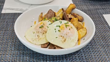 A bowl of food with eggs, potatoes, and meat.