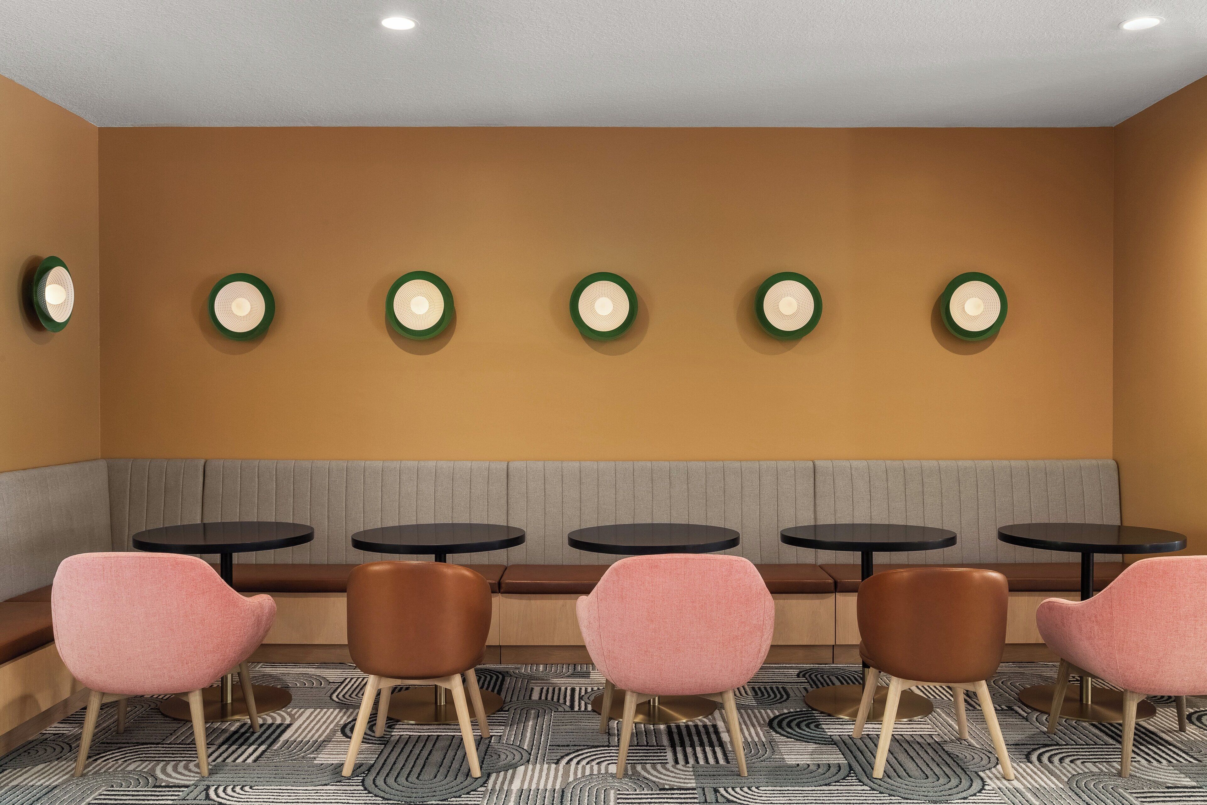 A seating area with a bench and six tables, each with a chair.