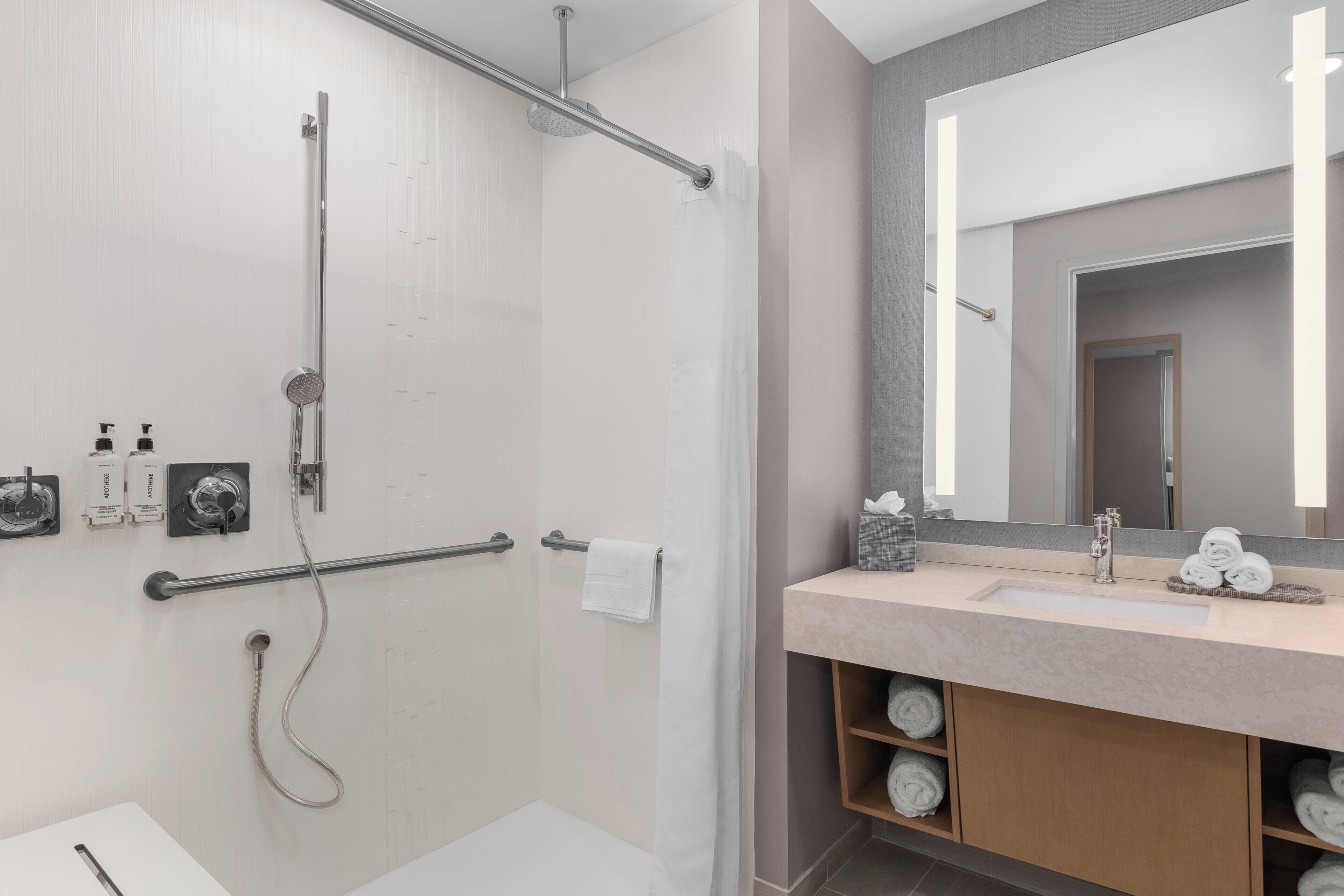 A modern bathroom with a shower, a sink, and a mirror.