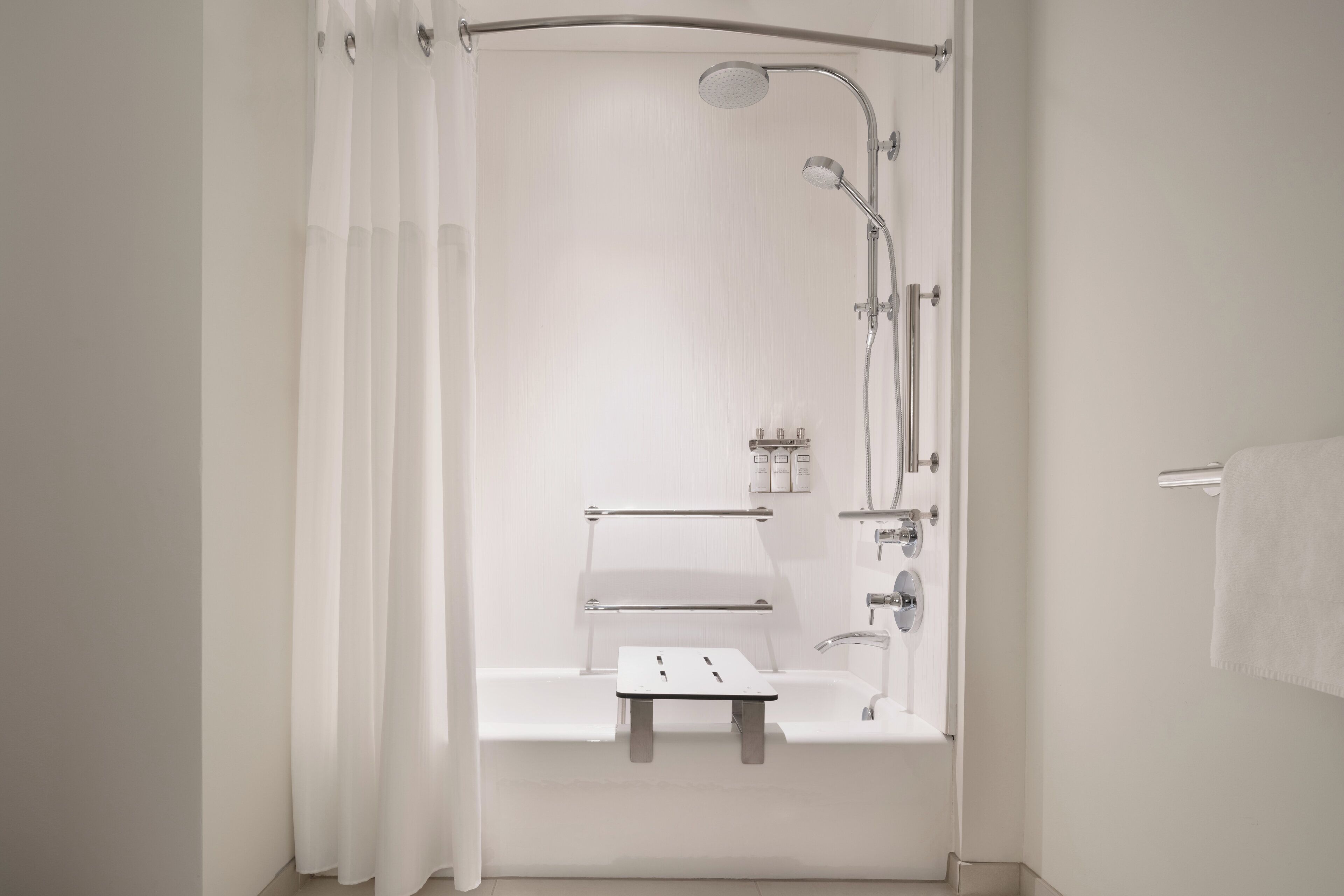 Une salle de bain moderne équipée d’une douche, d’un porte-serviettes et d’une petite étagère où sont rangés les articles de toilette.