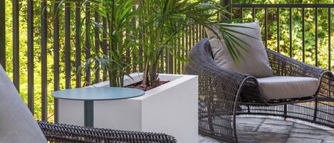 A patio area with wicker furniture, a round table, and a potted plant.