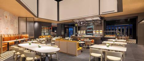 Un ristorante moderno con soffitti alti, diverse aree pranzo e un bar.