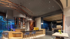Una cocina moderna con cañerías de cobre, una isla central con taburetes y vistas a un espacio exterior.
