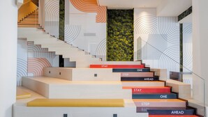 Una escalera moderna con los escalones marcados con 'STAY', 'ONE', 'STEP' y 'AHEAD'.