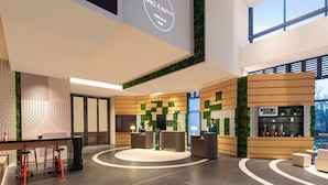Un moderno vestíbulo de hotel con mostrador de recepción, área de descanso y una pantalla grande mostrando un mensaje de bienvenida.