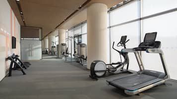 A modern gym with treadmills, elliptical machines, and weight equipment.
