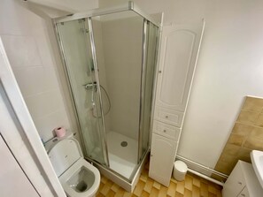 Une petite salle de bain avec une douche à parois de verre, des toilettes et un lavabo.