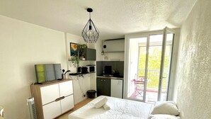 Ein Schlafzimmer mit Bett, Fernseher, Schreibtisch und einer Küchenzeile.