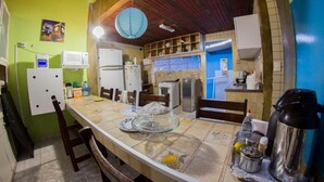 A kitchen with a dining table, chairs, and various kitchen appliances. - Cosmopolitan Hostel (Recife)