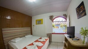 A hotel room with a bed, a TV, a desk, and a window with curtains. - Cosmopolitan Hostel (Recife)
