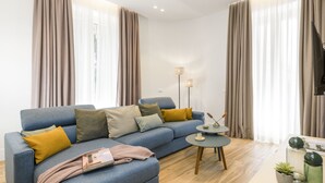 A modern living room with a blue sofa, a small round table, and a flat-screen TV. - Domus Augustea - Cesare (Rome)