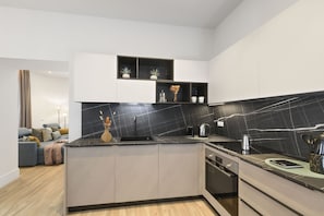A modern kitchen with a black marble backsplash, white cabinetry, and a built-in dishwasher. - Domus Augustea - Cesare (Rome)