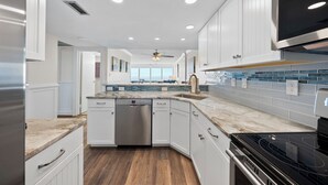 A modern kitchen with white cabinetry, a stainless steel dishwasher, and a black stove.