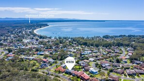 Luchtbeeld van een kustgebied met woonhuizen, met een opvallend label voor Huskisson Shops/Cafes en een markering voor Jervis Bay.
