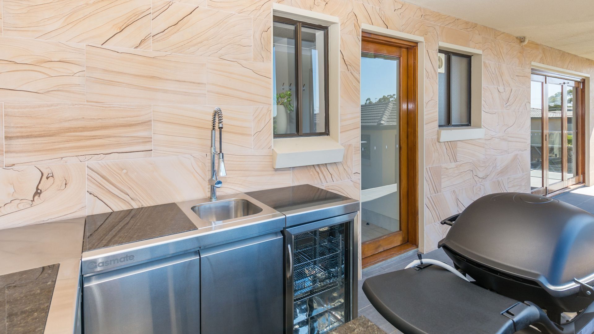 A modern kitchen with marble backsplash, stainless steel appliances, and a built-in dishwasher.