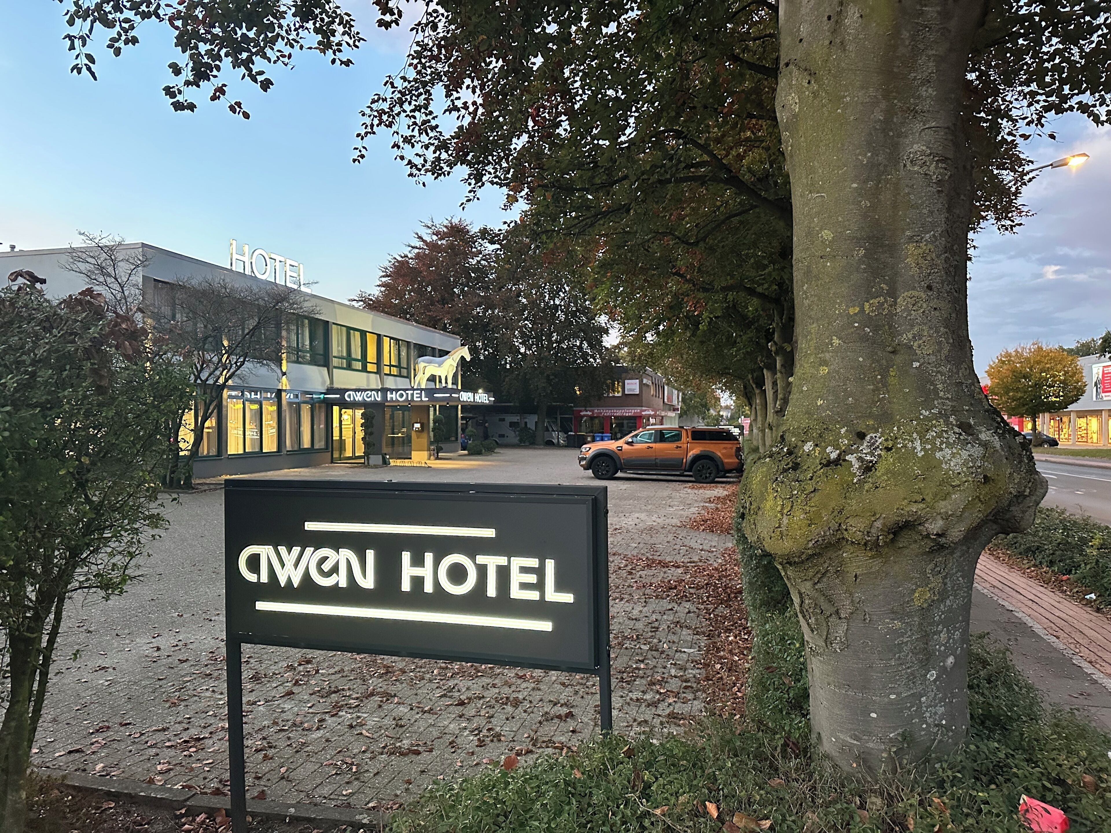 A sign for the Cwien Hotel with a modern building in the background.