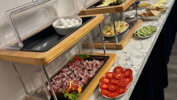 Un buffet proposant une variété de plats, notamment des viandes, des fromages et des fruits.