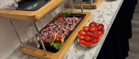 A buffet setup with various food items including meats, cheeses, and fruits.