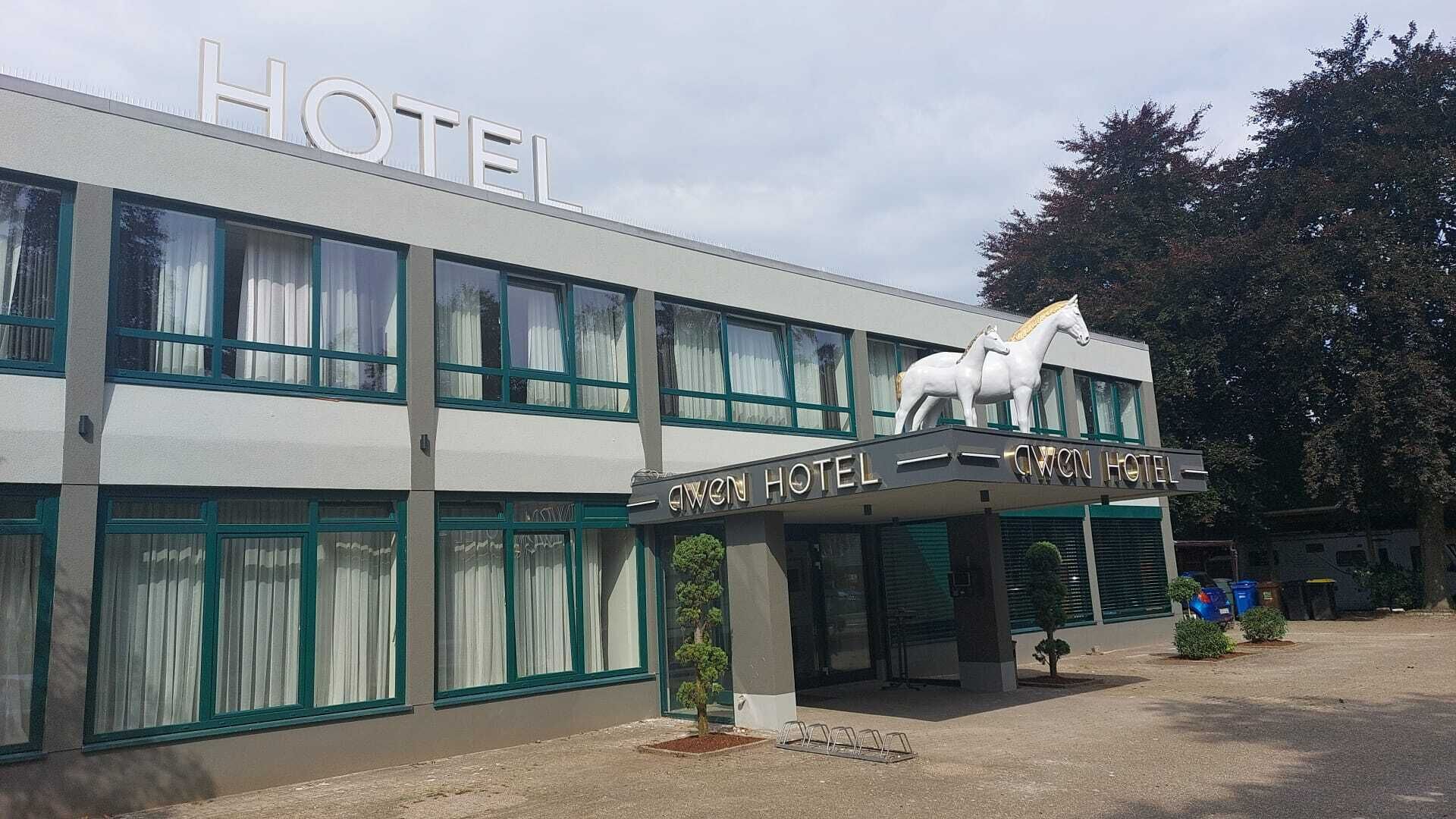 A hotel building with a sign reading "Aven Hotel" and a horse statue on the roof.