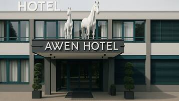 The exterior of the Awen Hotel with a modern design, featuring two horse statues at the entrance and a clear sign above the doors.