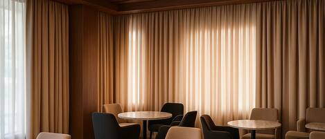 A room with wooden ceiling beams, a checkered floor, and multiple round tables and chairs.