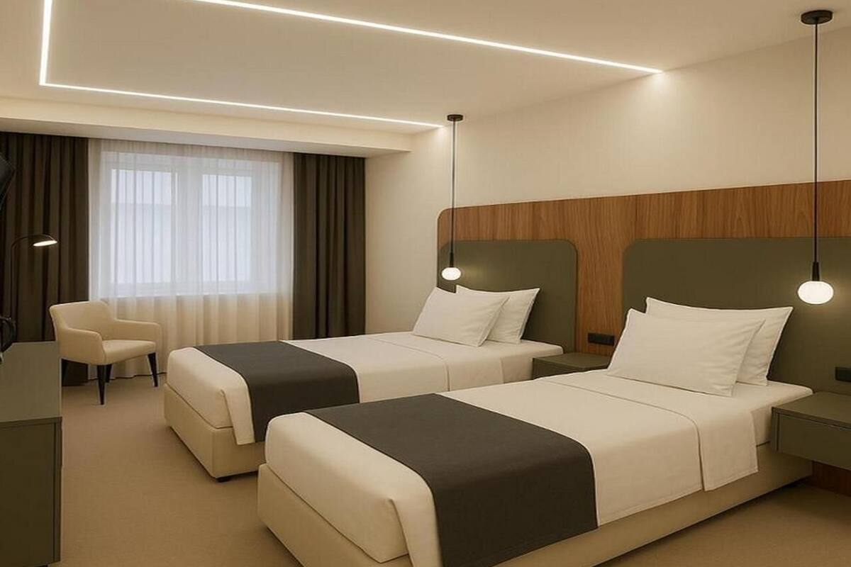 A hotel room with two beds, a desk, a chair, and a large window with curtains.