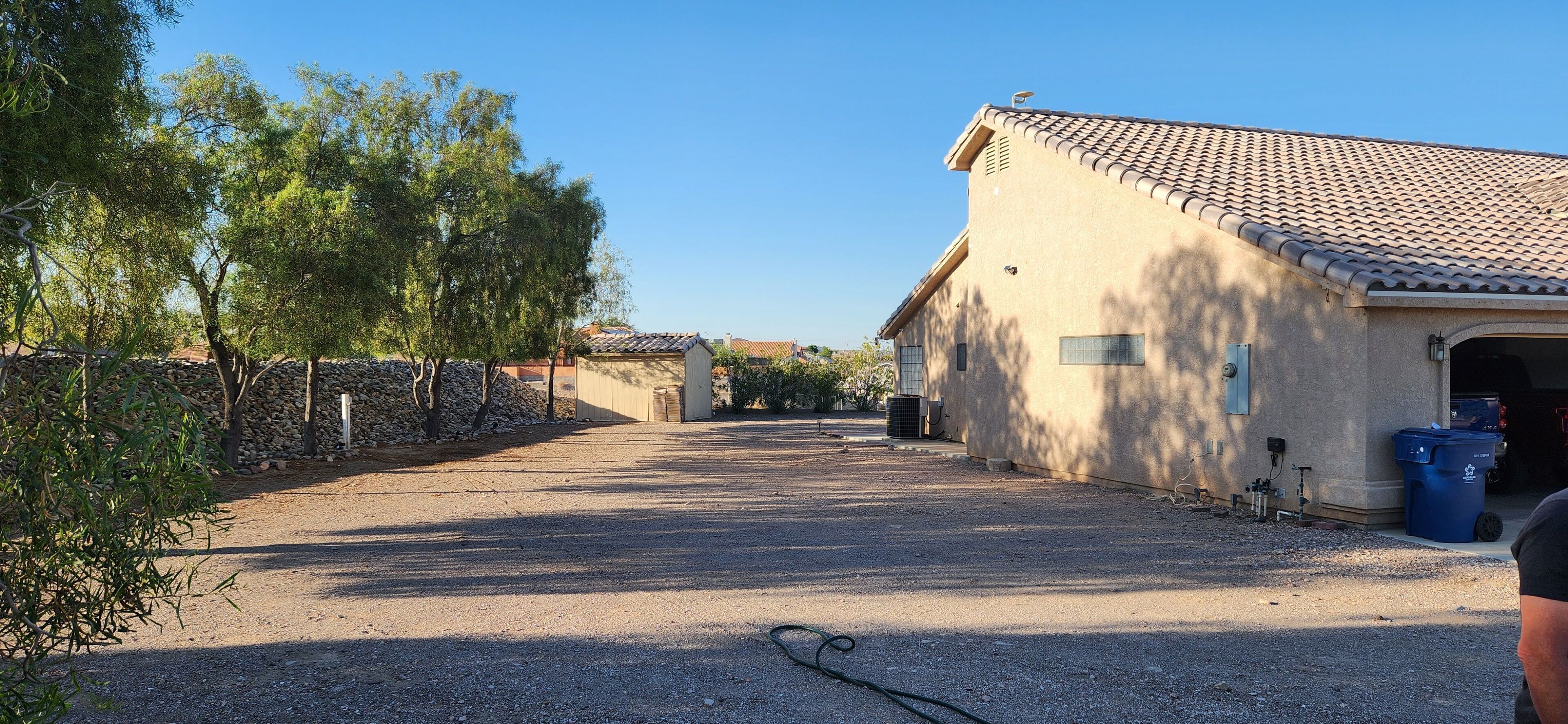 Une allée de gravier mène à un bâtiment doté d’un toit en tuiles et d’un mur en pierre sur l’un de ses côtés.