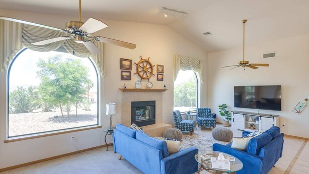 A spacious living room with a fireplace, two sofas, a TV, and a ceiling fan. - Casa Vista -- Home with a View (Bullhead City)